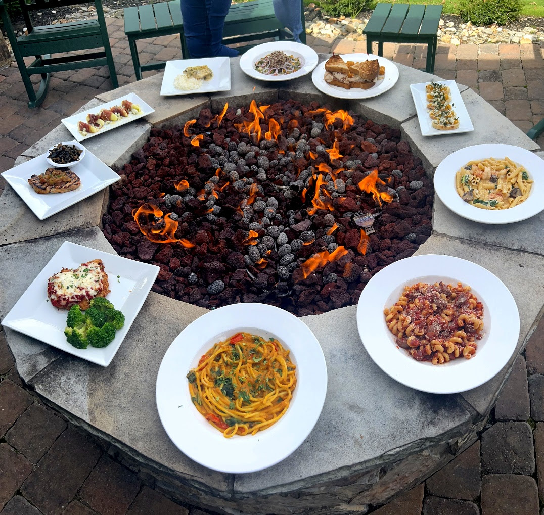 A circular stone fire pit with plates of food on it

Description automatically generated